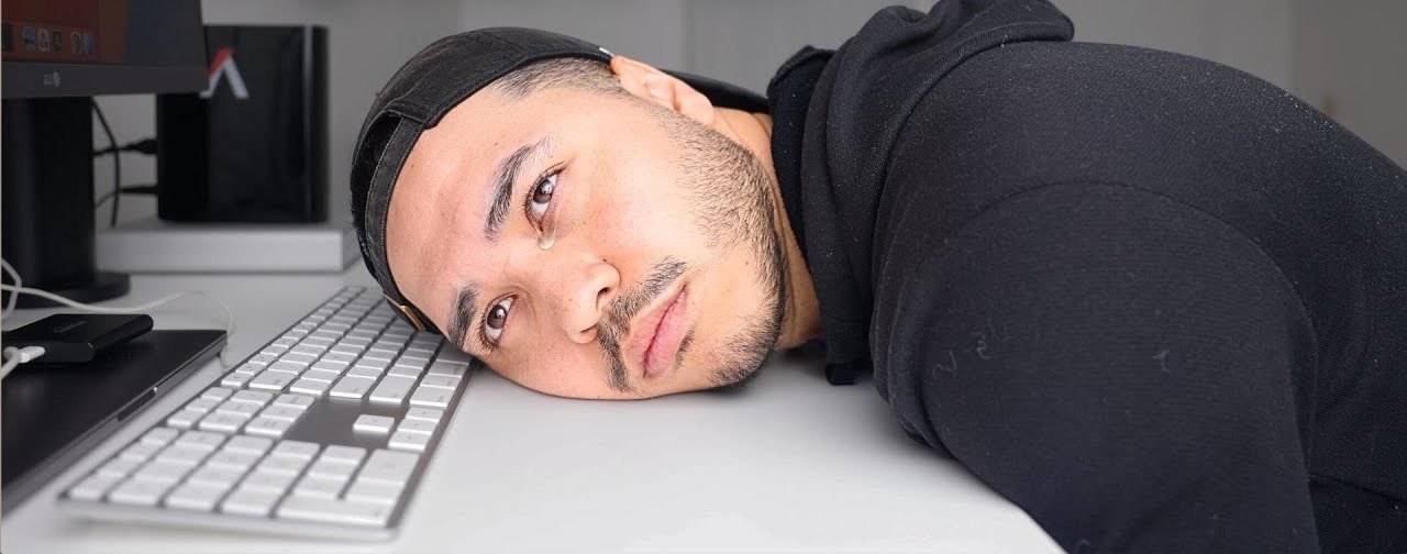 Ramon resting his head on his keyboard at his desk